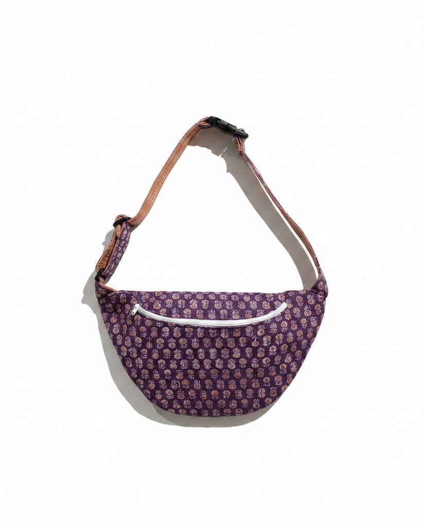Devï Studios SARL Sac banane banane en coton violet à imprimé floral, avec fermeture éclair blanche et sangle réglable.