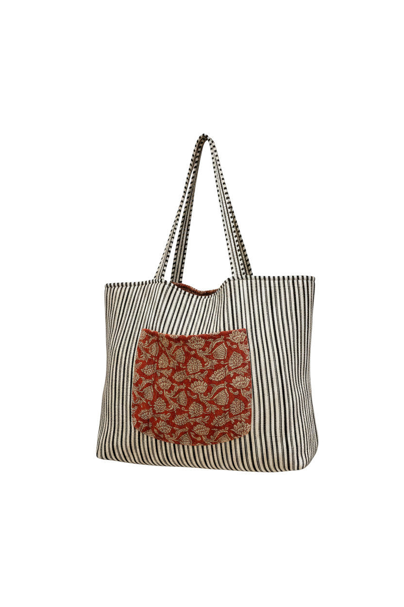 Devï Studios SARL tote bag en coton réversible rayée noir et blanc avec une poche avant imprimée florale rouge.